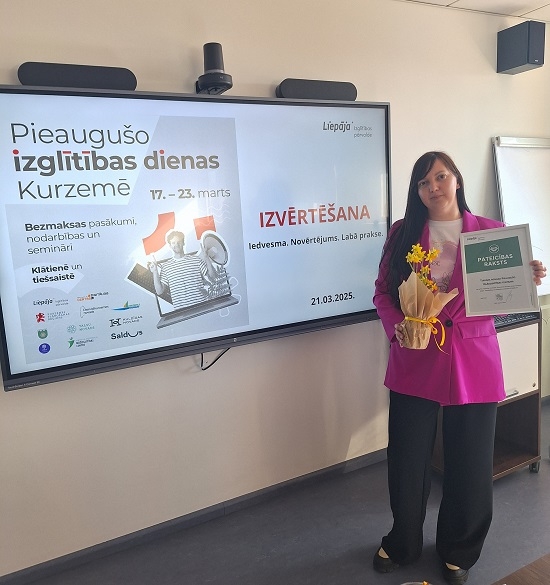 Pieaugušo tālākizglītības centra vadītāja Alise Šmēla rokās ar Pateicības rakstu.