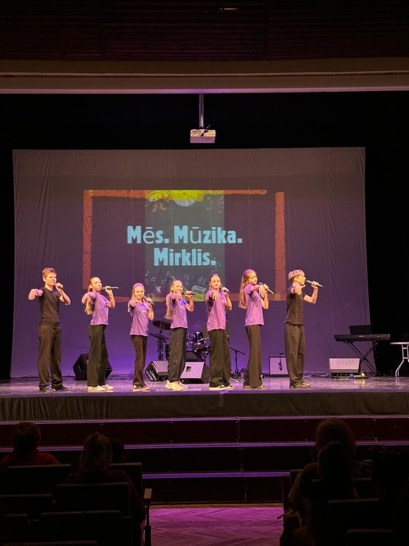uzstājas jauniešu grupa ar violetiem tkrekliem 